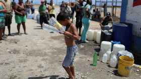 Un niño lleva botellas con agua en una planta de desalinización en La Guaira.