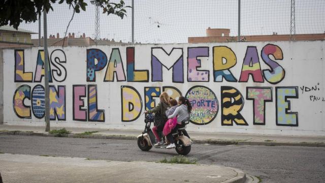 Una mujer conduce por la barriada cordobesa de Las Palmeras una moto con tres niñas menores de edad encima.