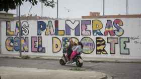 Una mujer conduce por la barriada cordobesa de Las Palmeras una moto con tres niñas menores de edad encima.