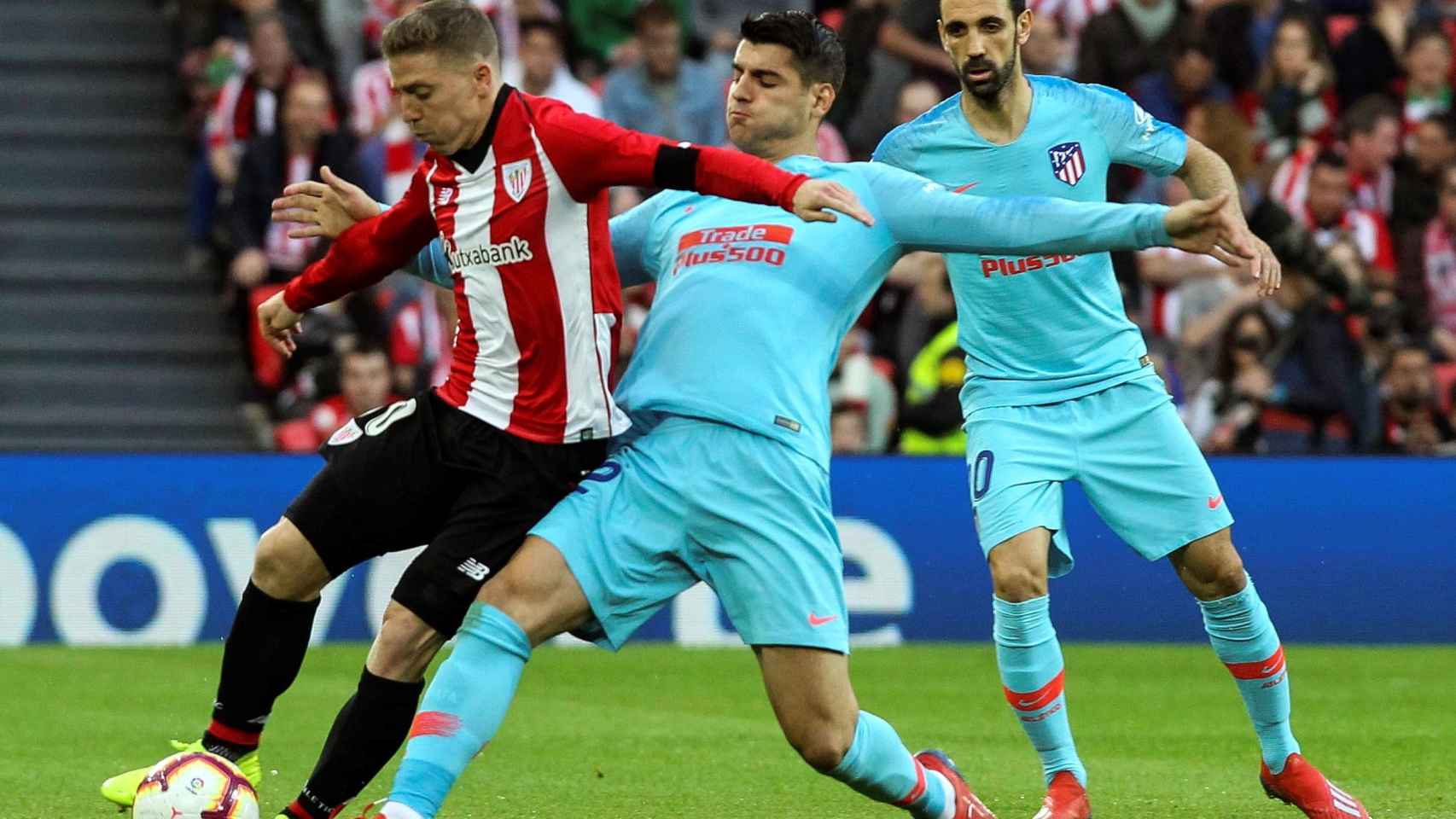 Iker Muniain intenta llevarse el balón ante el acoso de Álvaro Morata