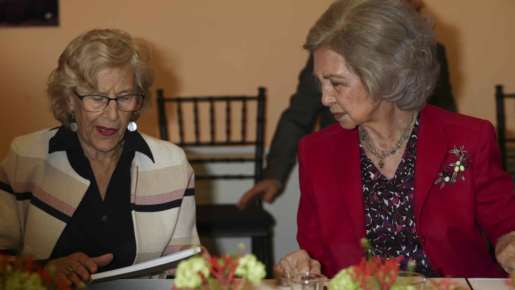 Manuela Carmena y la reina Sofía sentadas juntas durante el evento, mostrando una gran complicidad.