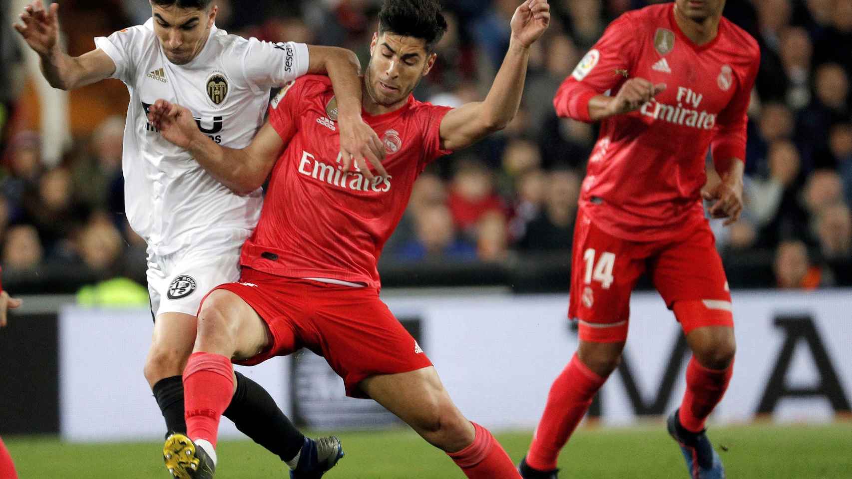 Carlos Soler pelea un balón con el centrocampista del Real Madrid Marco Asensio
