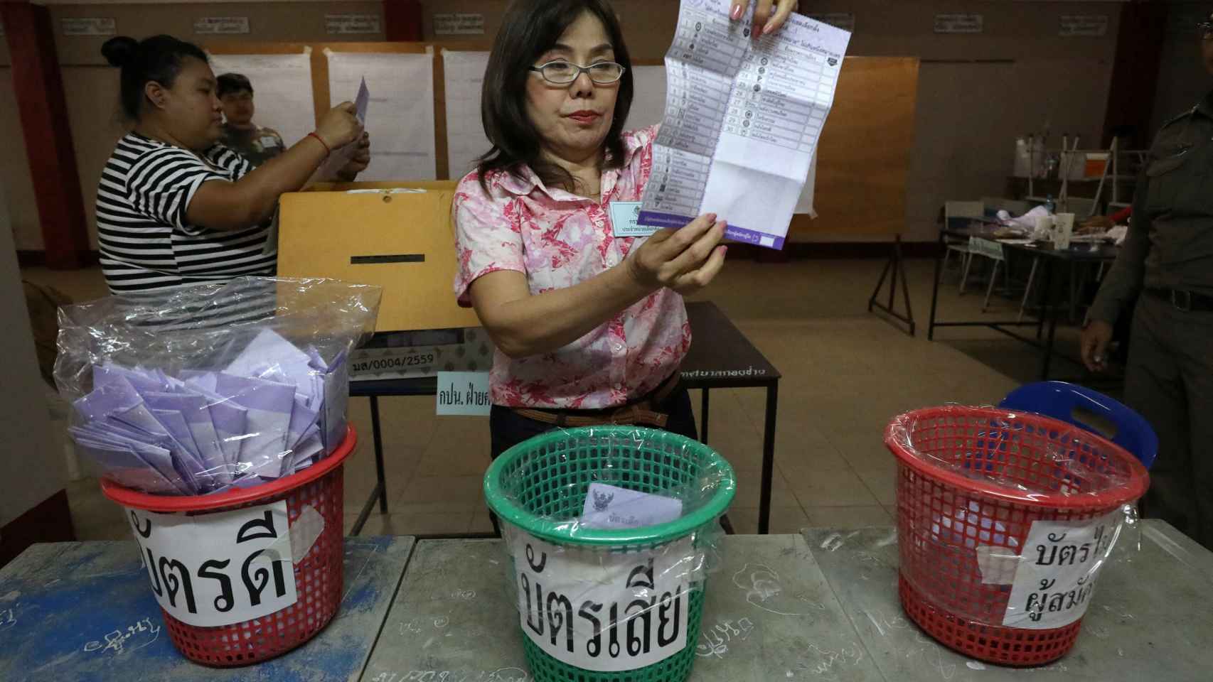 Una mujer sujeta una papeleta en una mesa electoral en Tailandia.