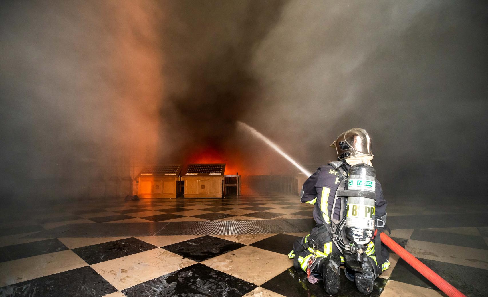 Un bombero intentando controlar las llamas en la catedral parisina.