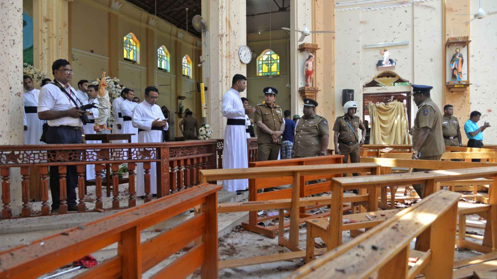 Policías y sacerdotes católicos se paran dentro de la iglesia después de la explosión en Negombo