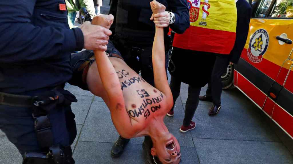 La activista de Femen fue desalojada en volandas de la plaza por agentes de la Policía Nacional.