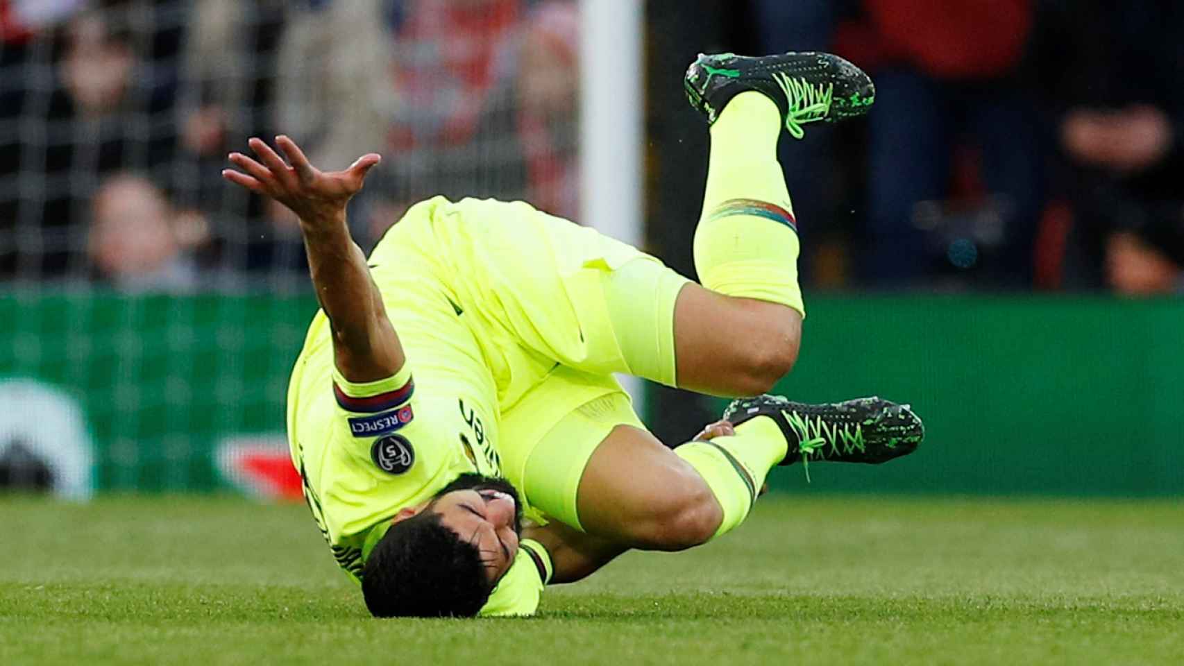 Luis Suárez rueda sobre el césped tras caer en una acción contra un jugador del Liverpool