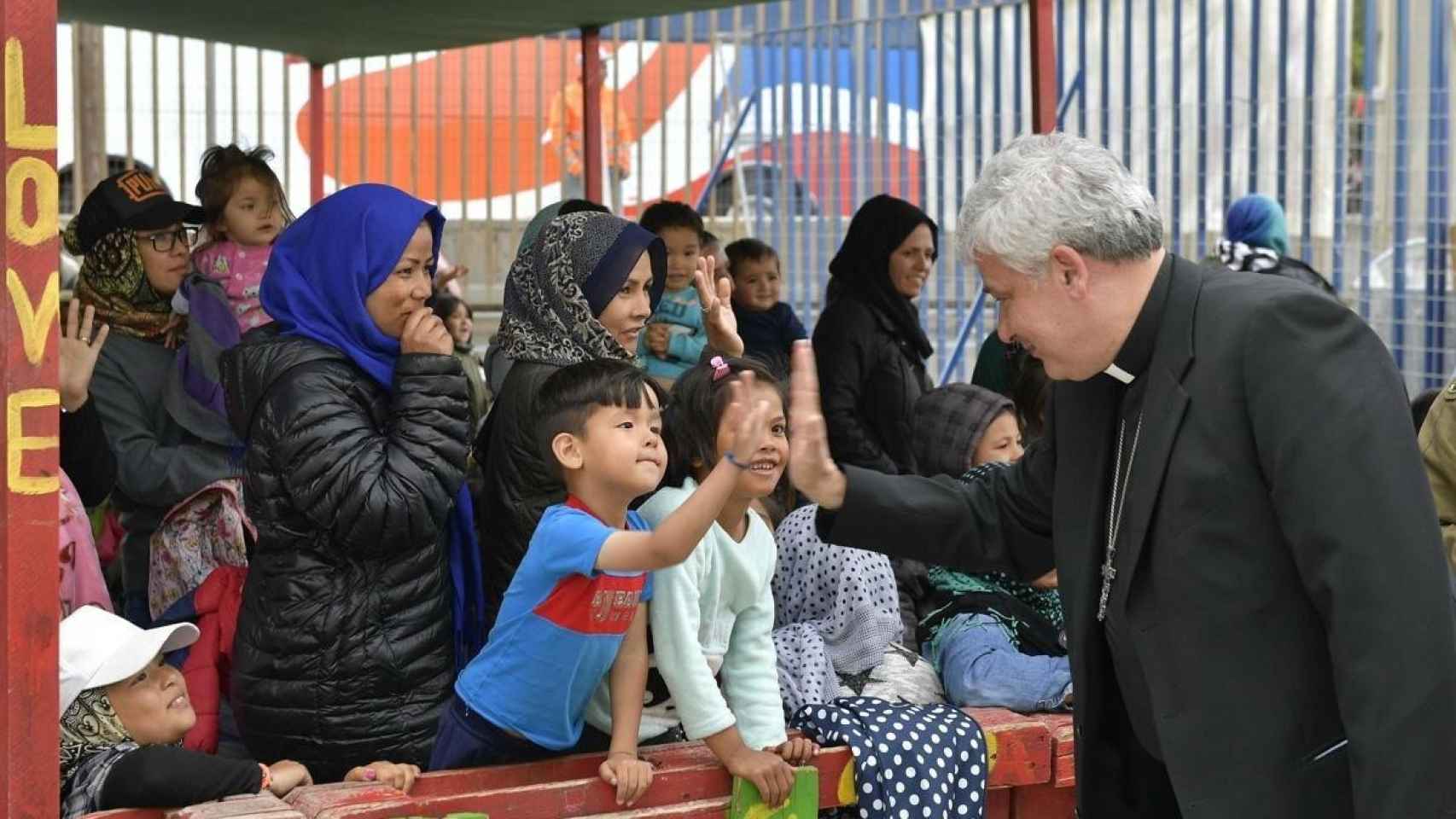 El limosnero del Papa, Konrad Krajewski, saluda a un niño en un campamento de refugiados en Grecia.
