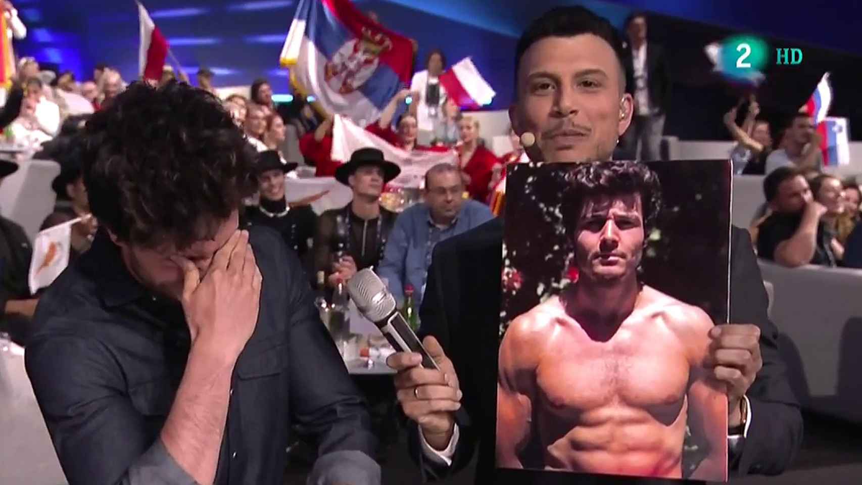 Miki Núñez, en el momento en que el presentador de Eurovisión le enseña su foto sin camiseta.