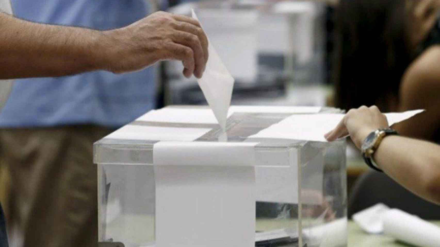 Una persona introduce su voto en las urnas.