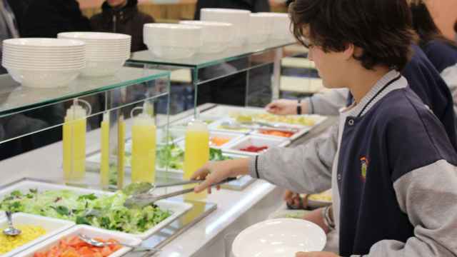 Un alumno escogiendo comida en un comedor escolar.