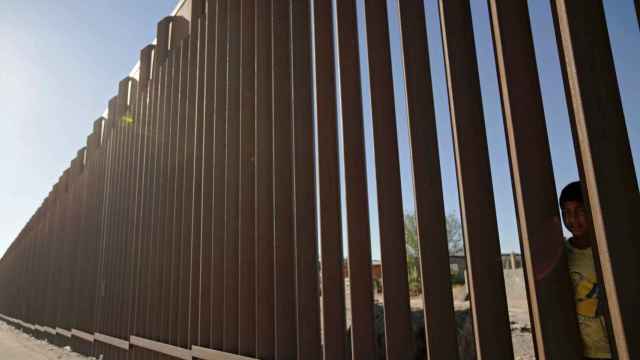 Un niño mira a través del muro que separa la frontera entre EEUU y México.