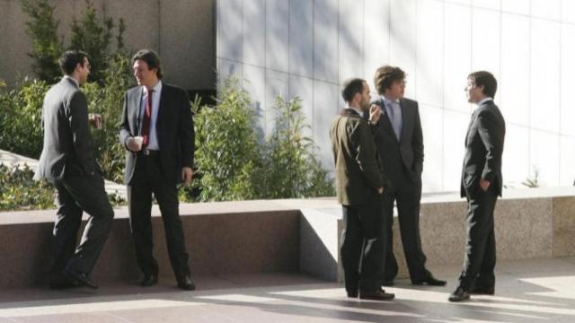 Trabajadores fumando y tomando café en la puerta de una empresa.