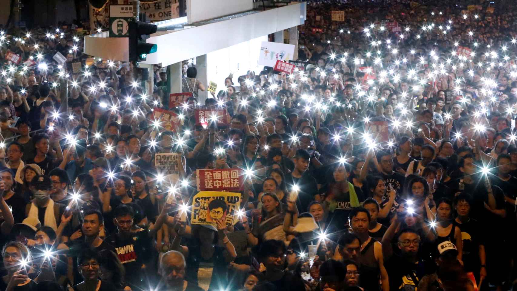 Manifestantes encienden las linternas de sus móviles durante la protesta por la noche.