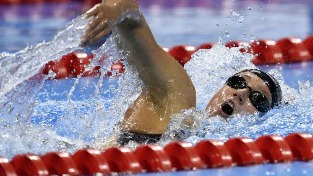 Una nadadora compitiendo en una piscina olímpica.
