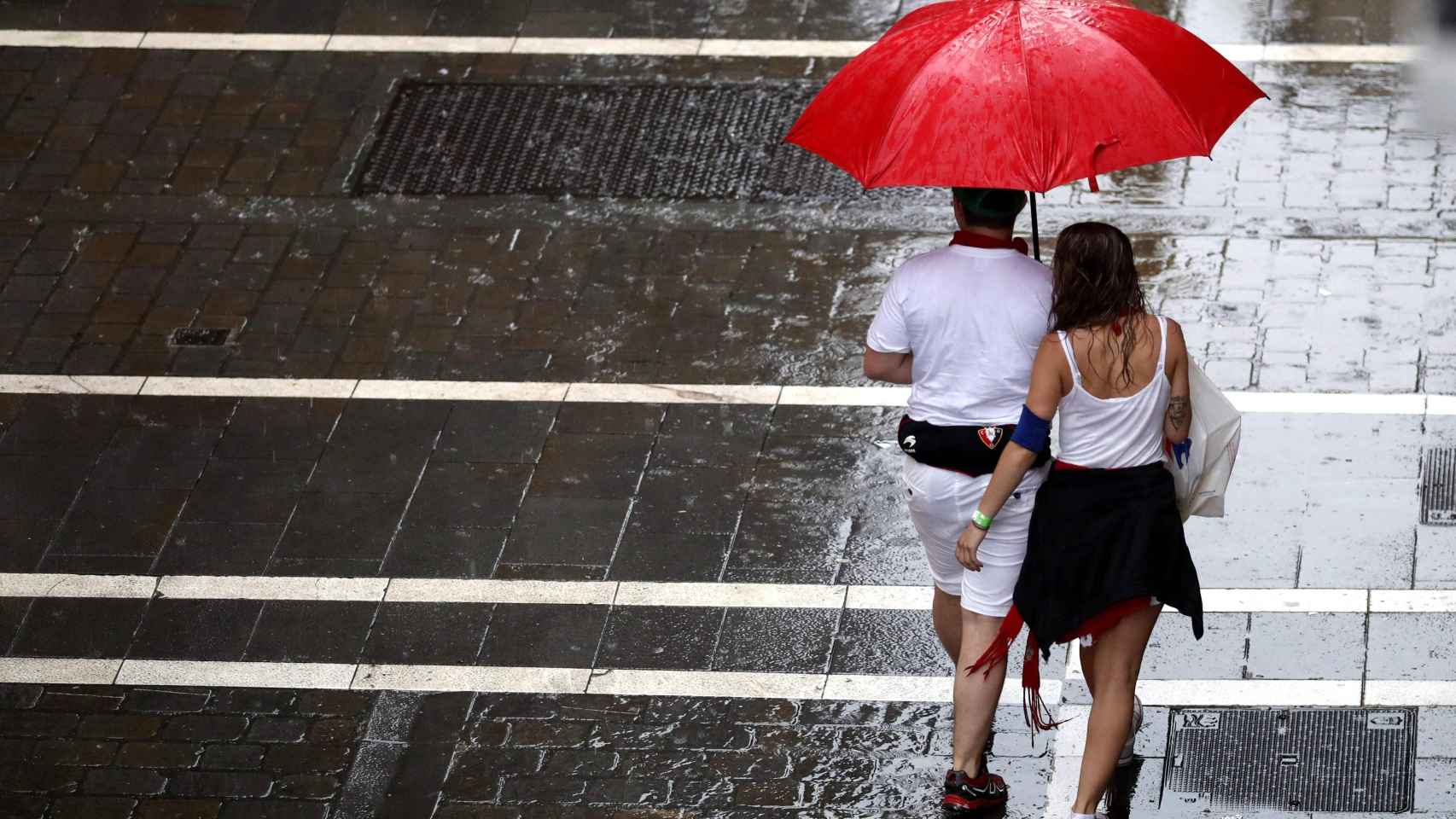 Dos personas se protegen de la lluvia en una de las céntricas calles de Pamplona. EFE/ Javier Lizón