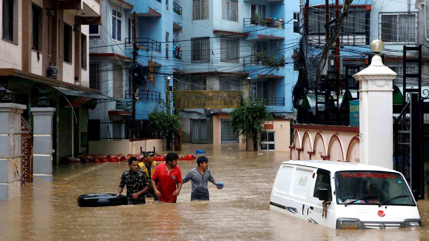 Tres hombres caminan en una calle inundada en Katmandú. / Reuters