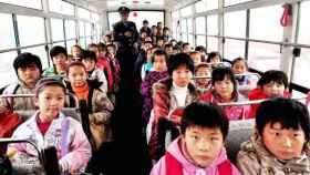 Un grupo de niños chinos de camino al colegio en un autobús escolar.
