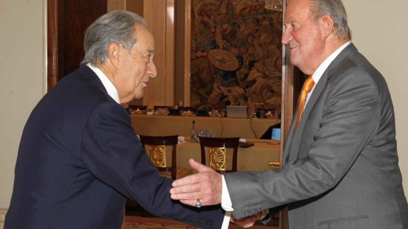 Juan Miguel Villar Mir le da la mano a Juan Carlos I.