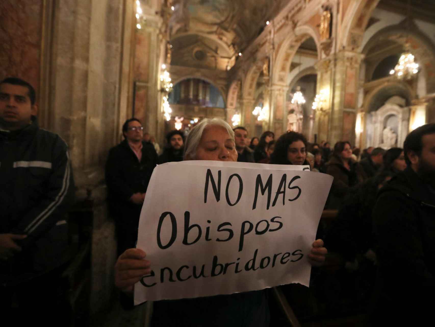 Una manifestane sosteniendo un letrero durante una misa en Santiago de Chile.
