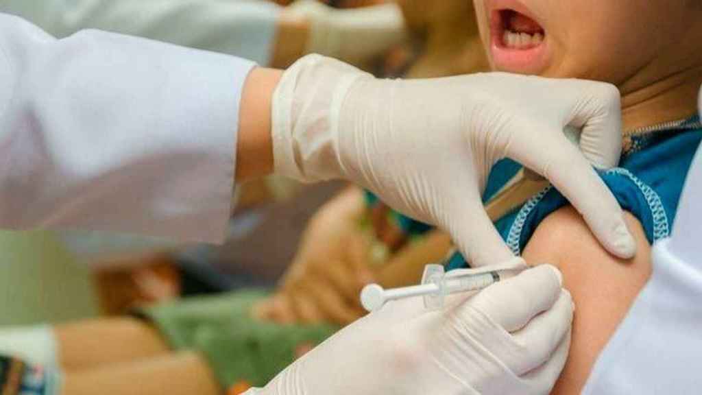 Un enfermero vacunando a un niño.