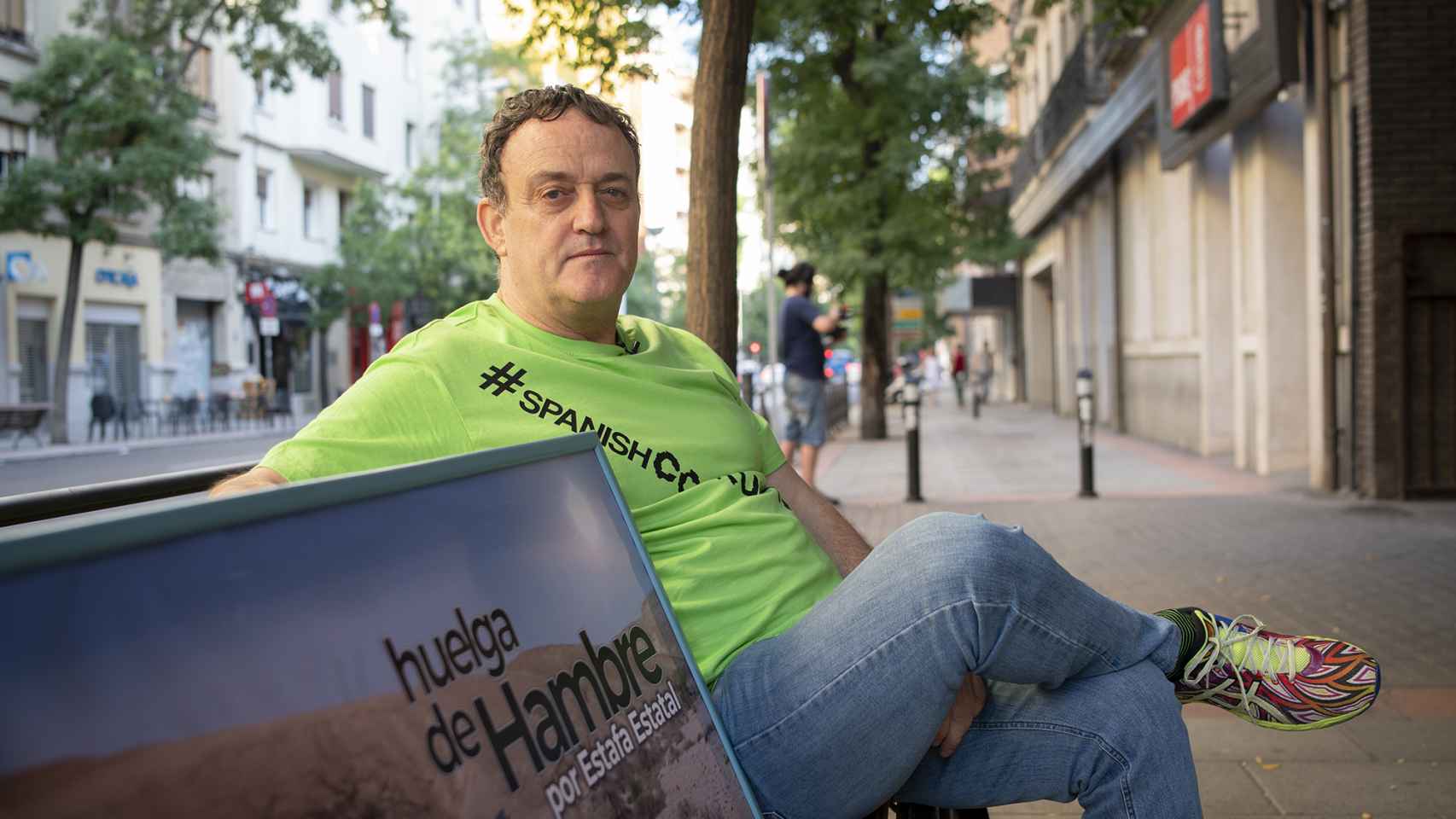 César Vea sostiene un cartel en el que asegura que ha sido víctima de una estafa estatal