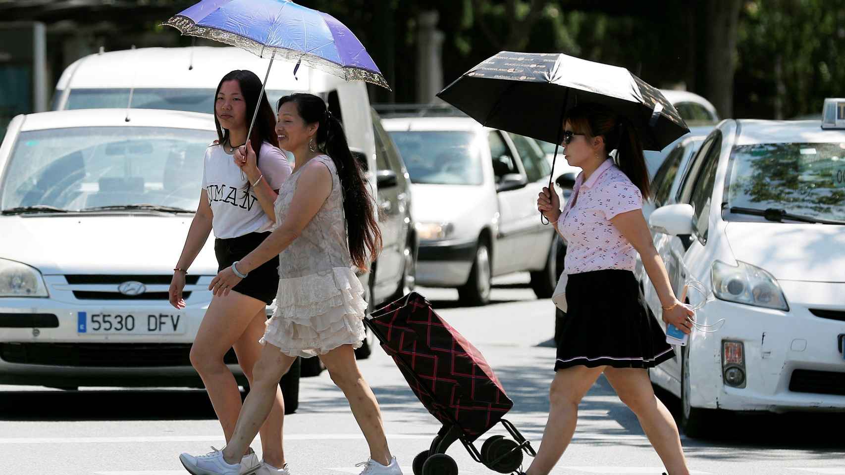 Tres mujeres se protegen del sol y del calor con sombrillas en Valencia. EFE/Kai Försterling