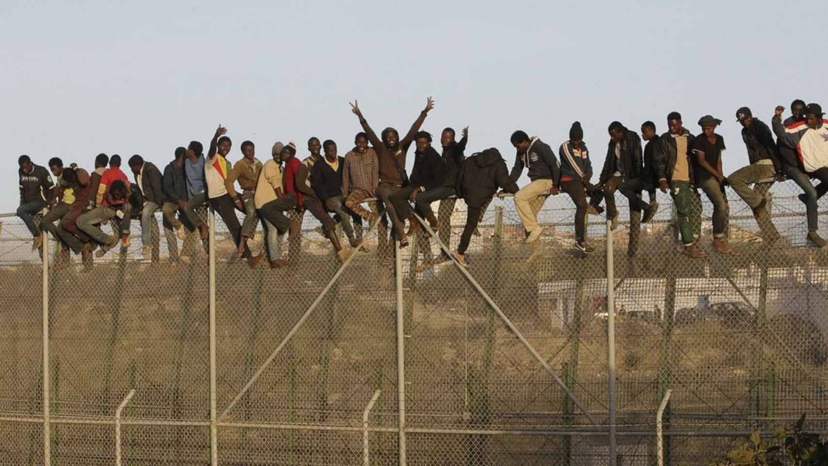 Inmigrantes encaramados a la valla fronteriza de Melilla.