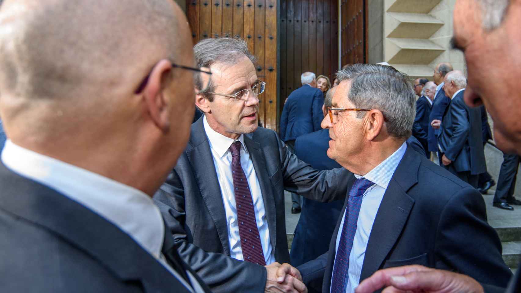 El presidente de CaixaBank, Jordi Gual, saluda al expresidente de Kutxabank, Mario Fernández.