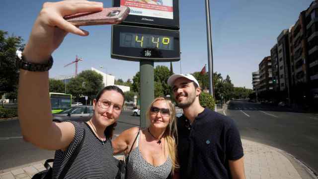 Unos turistas se fotografían con un termómetro del centro de Córdoba que indica 44 grados. EFE/ Salas.