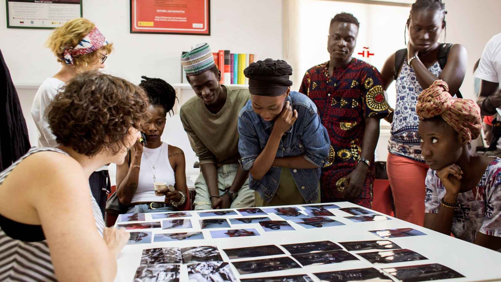 Alumnos y profesora analizan las fotografías de Koukambakana Mattieu Urielle durante el taller celebrado en el Aula Cervantes de Dakar.