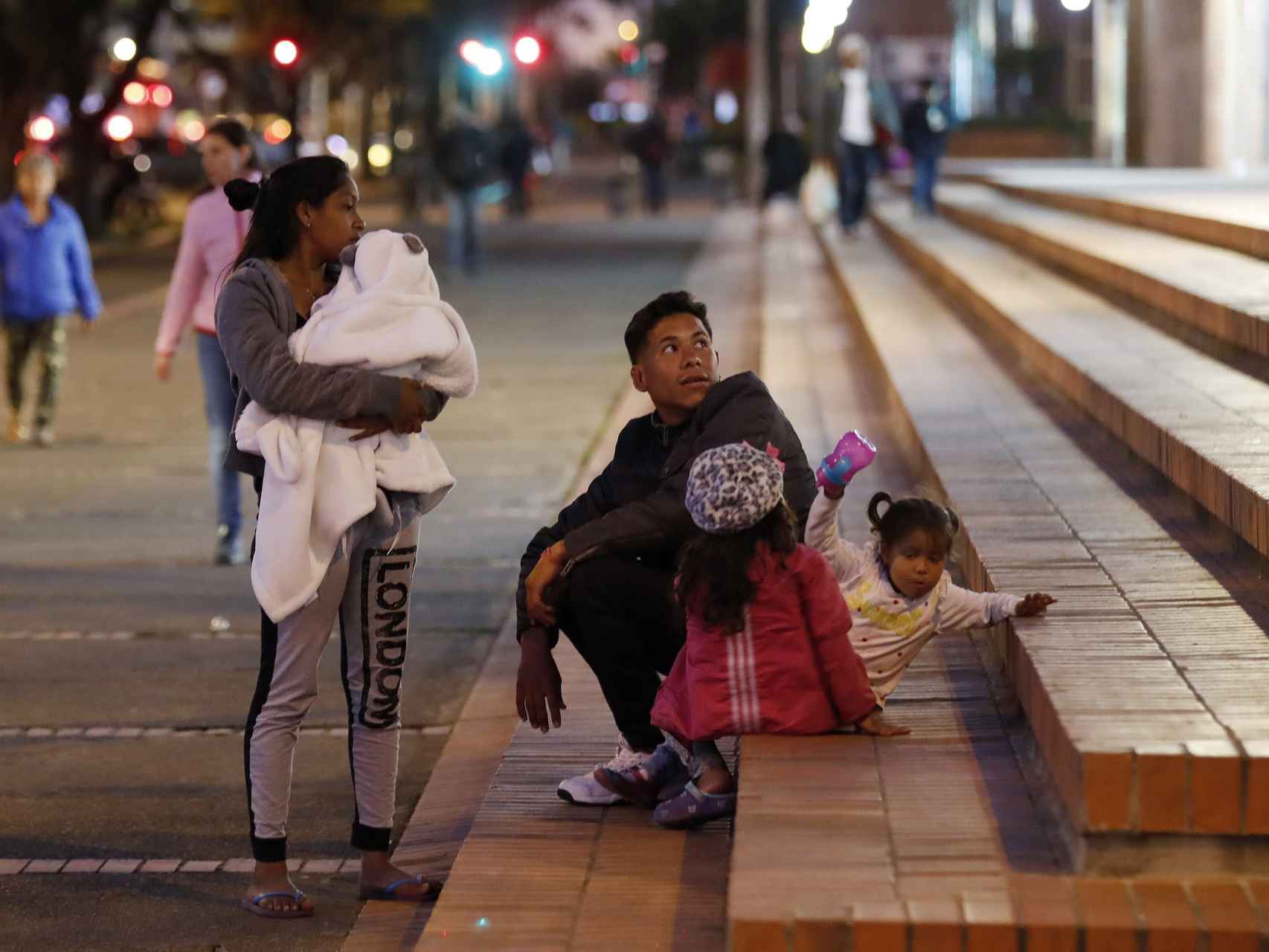 Una familia de venezolanos descansa en unas escaleras cercanas a la terminal de transportes de Bogotá.
