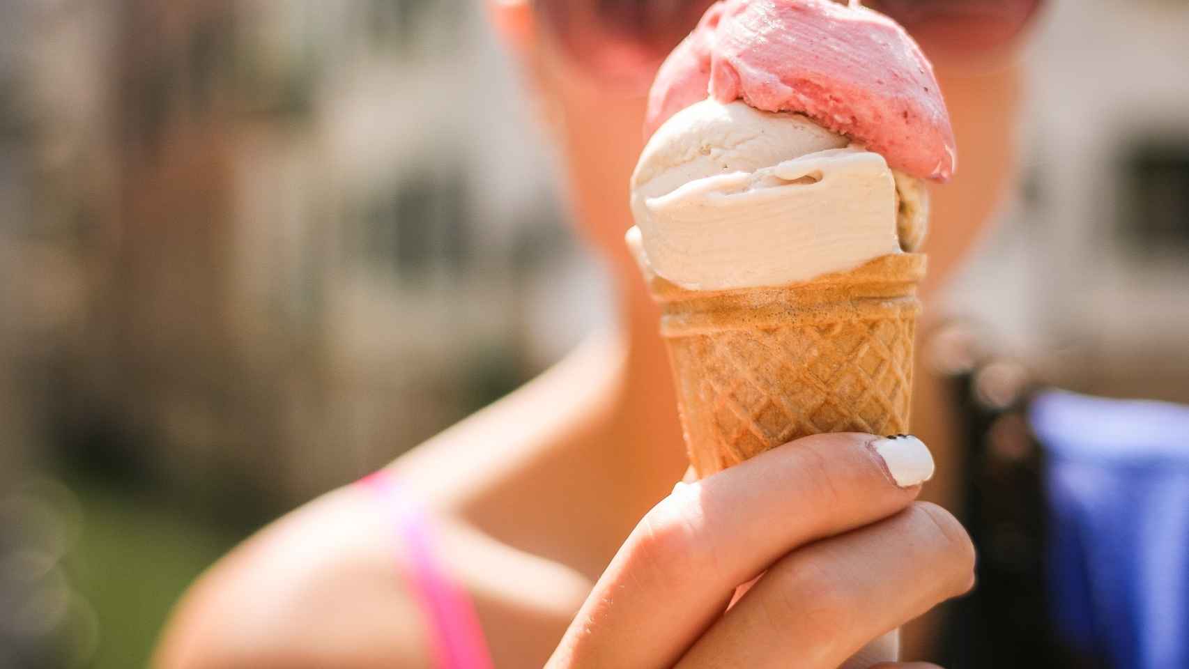 Una joven sostiene un helado de fresa con nata.