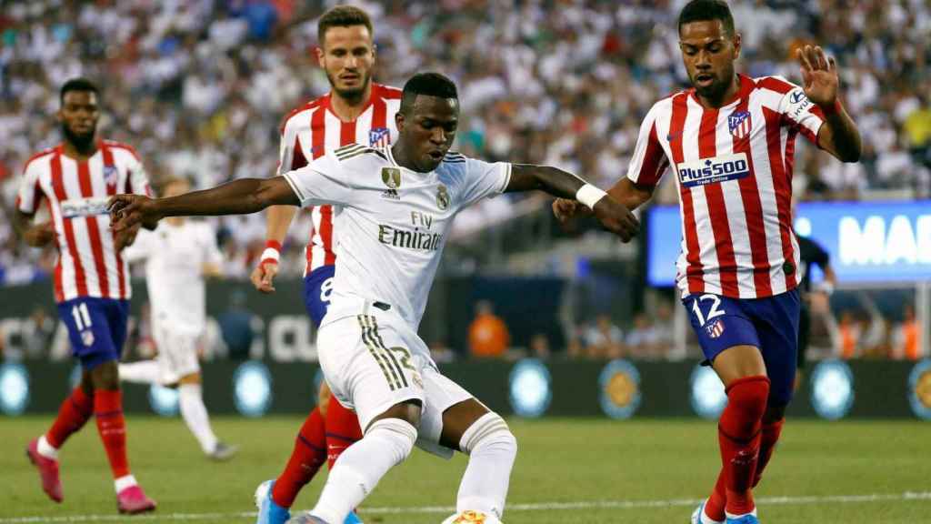 Vinicius intenta centrar entre dos jugadores del Atlético de Madrid