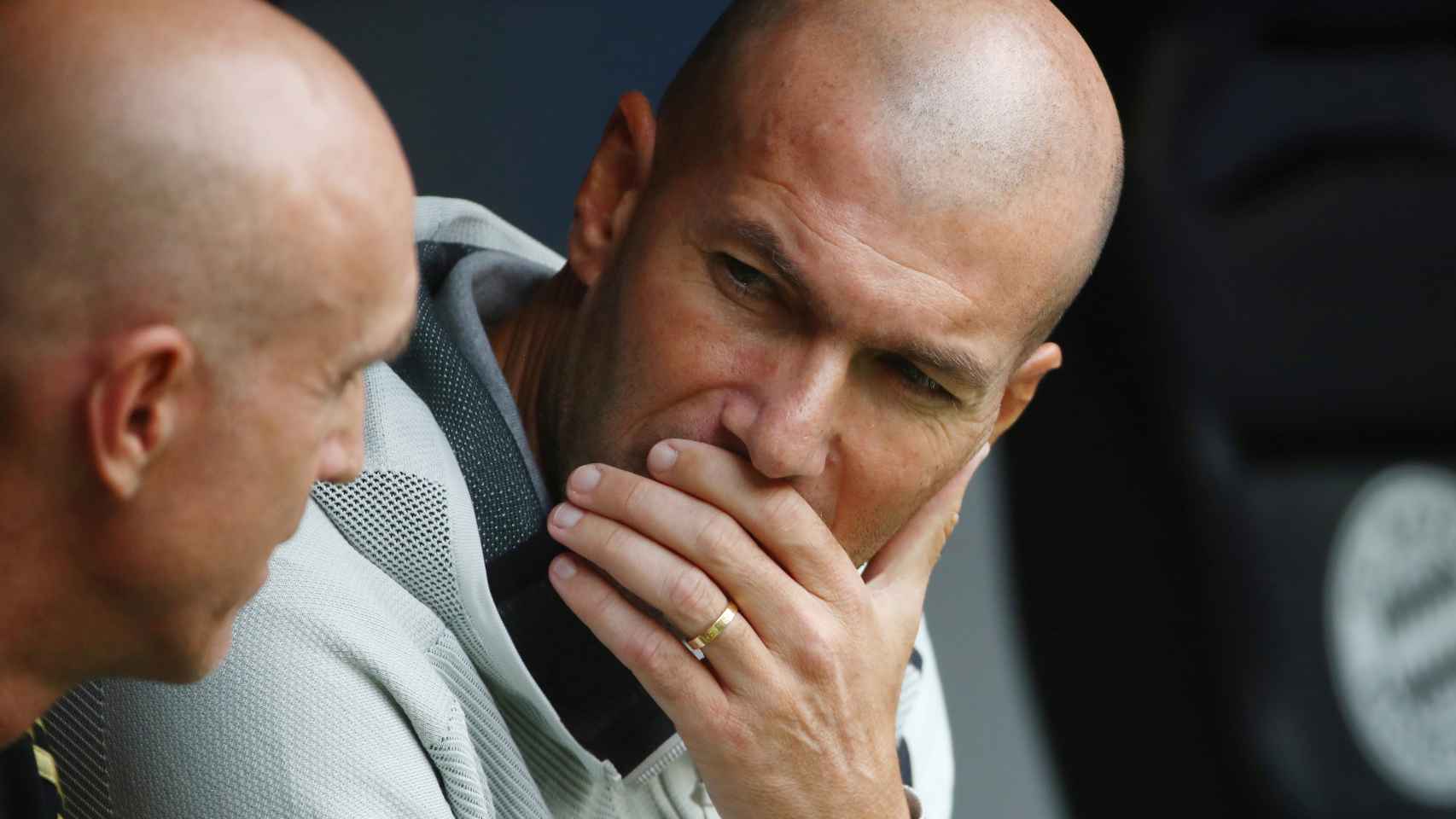 Zinedine Zidane habla con uno de sus ayudantes en el banquillo
