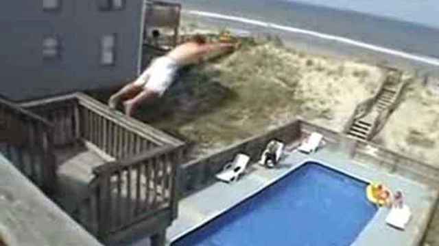 Un joven se lanza desde un balcón a una piscina.