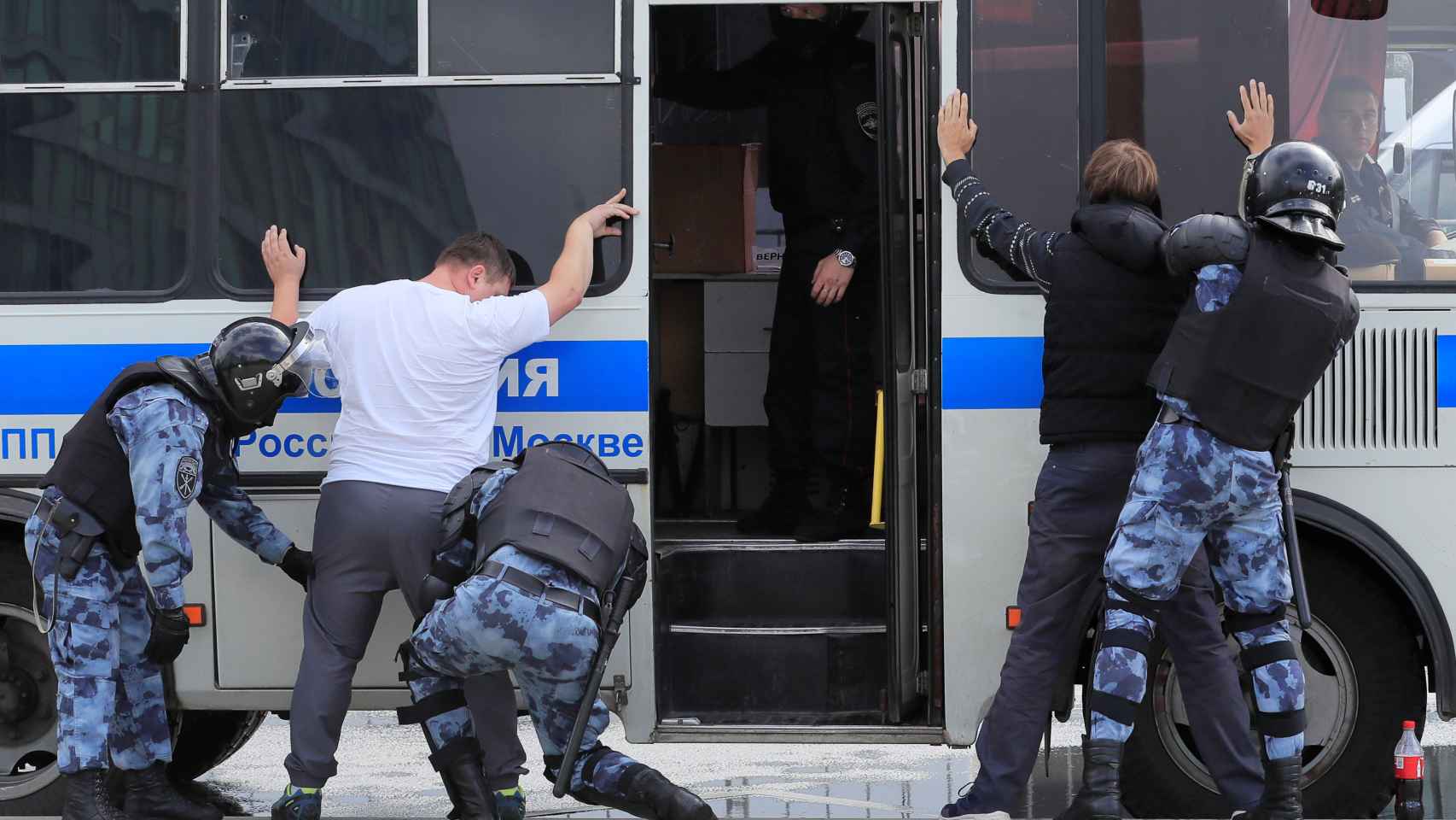 Varios policías cachean a unos manifestantes en Moscú.