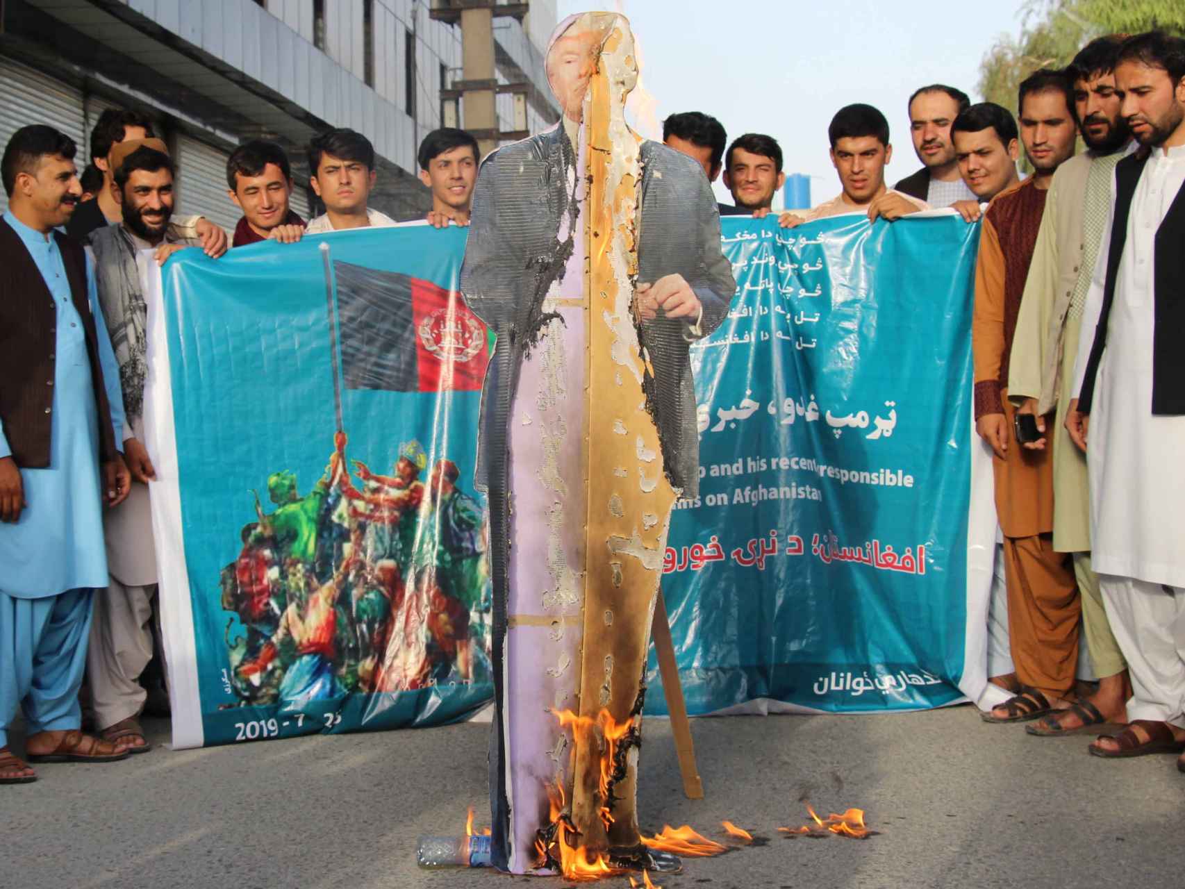 Varios afganos queman un retrato de Donald Trump.