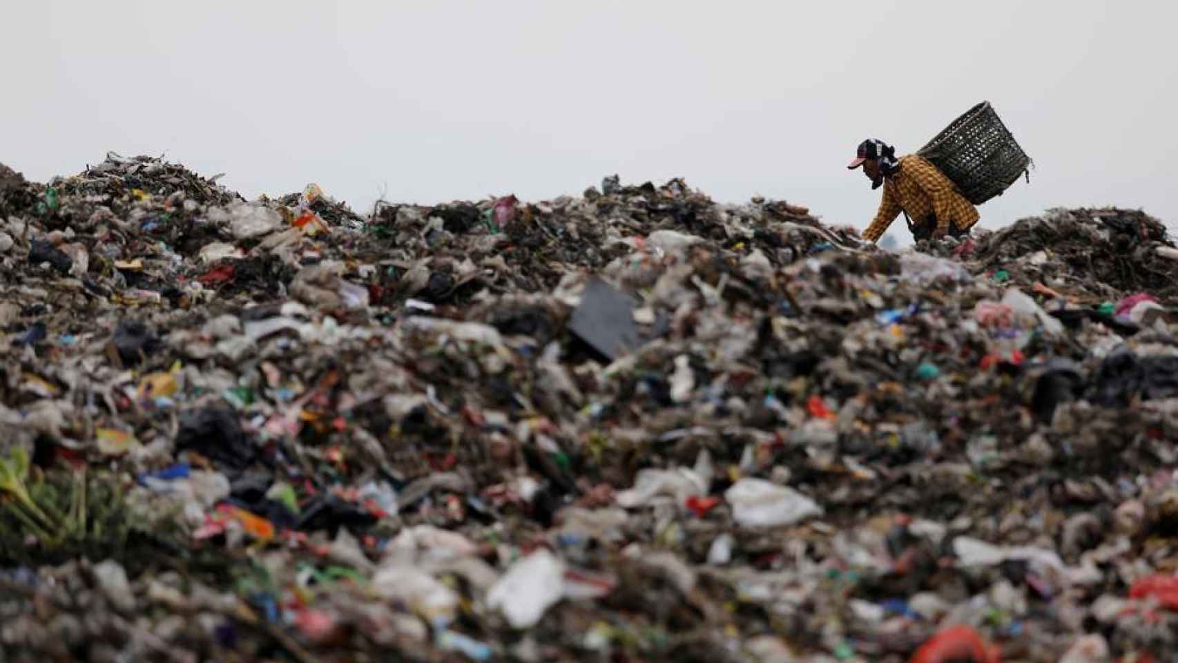 Un hombre busca plástico en una montaña de residuos en Indonesia.