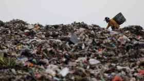 Un hombre busca plástico en una montaña de residuos en Indonesia.