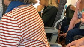 La señora con la camiseta de rayas está volando sin respaldo en su asiento