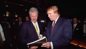Trump le enseña un libro a Clinton en junio del año 2000.