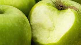 Una manzana verde con un mordisco en su parte exterior.