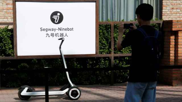 Man takes pictures of a semi-autonomous scooter KickScooter T60 that can return itself to charging stations without a driver, at a Segway-Ninebot product launch event in Beijing