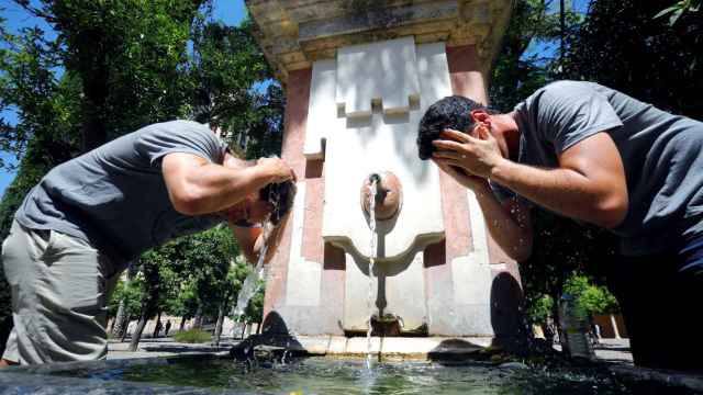 Unos turistas se refrescan en una fuente de Córdoba.