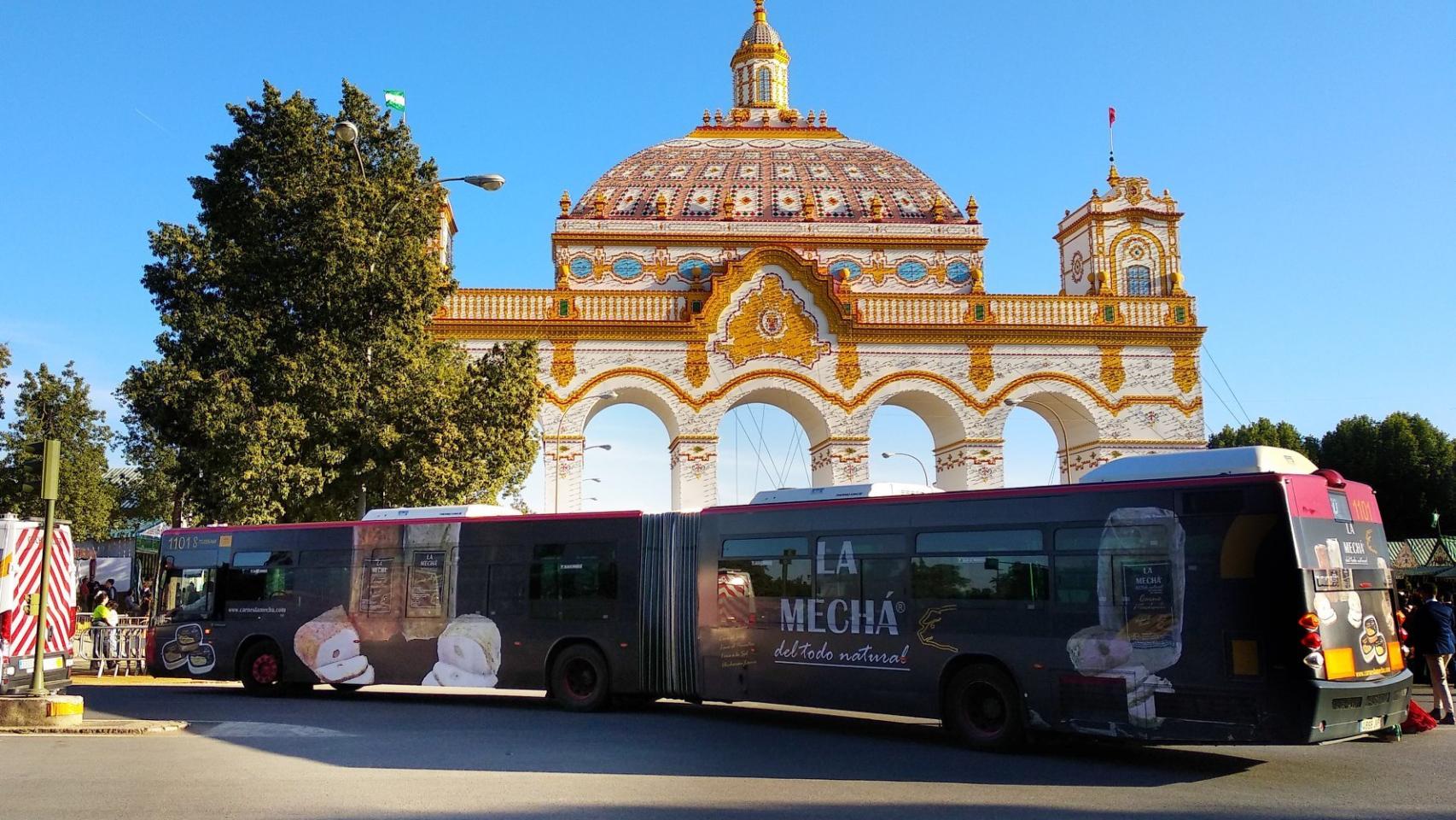 Un autobús con publicidad de La Mechá, frente a la puerta de la Feria de Abril.