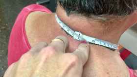 Una persona mide el cuello de una anciana con una cinta métrica.
