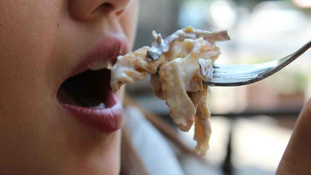 Una mujer se lleva a la boca un tenedor con comida.