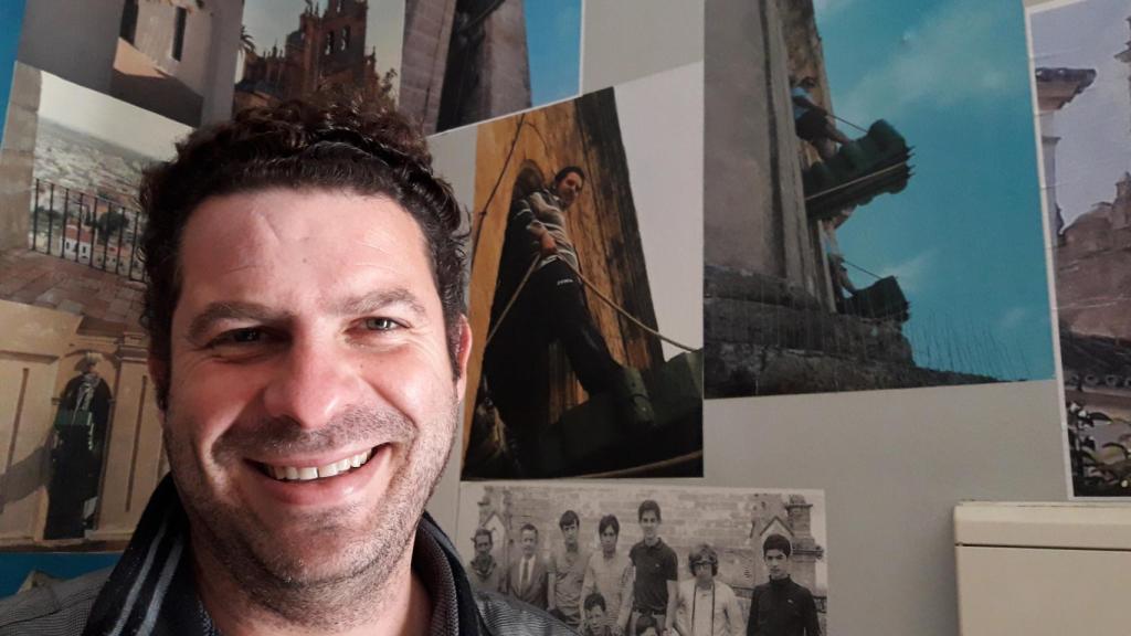 Carlos Palacios, junto a una foto en la que aparece subido a una campana en Utrera.