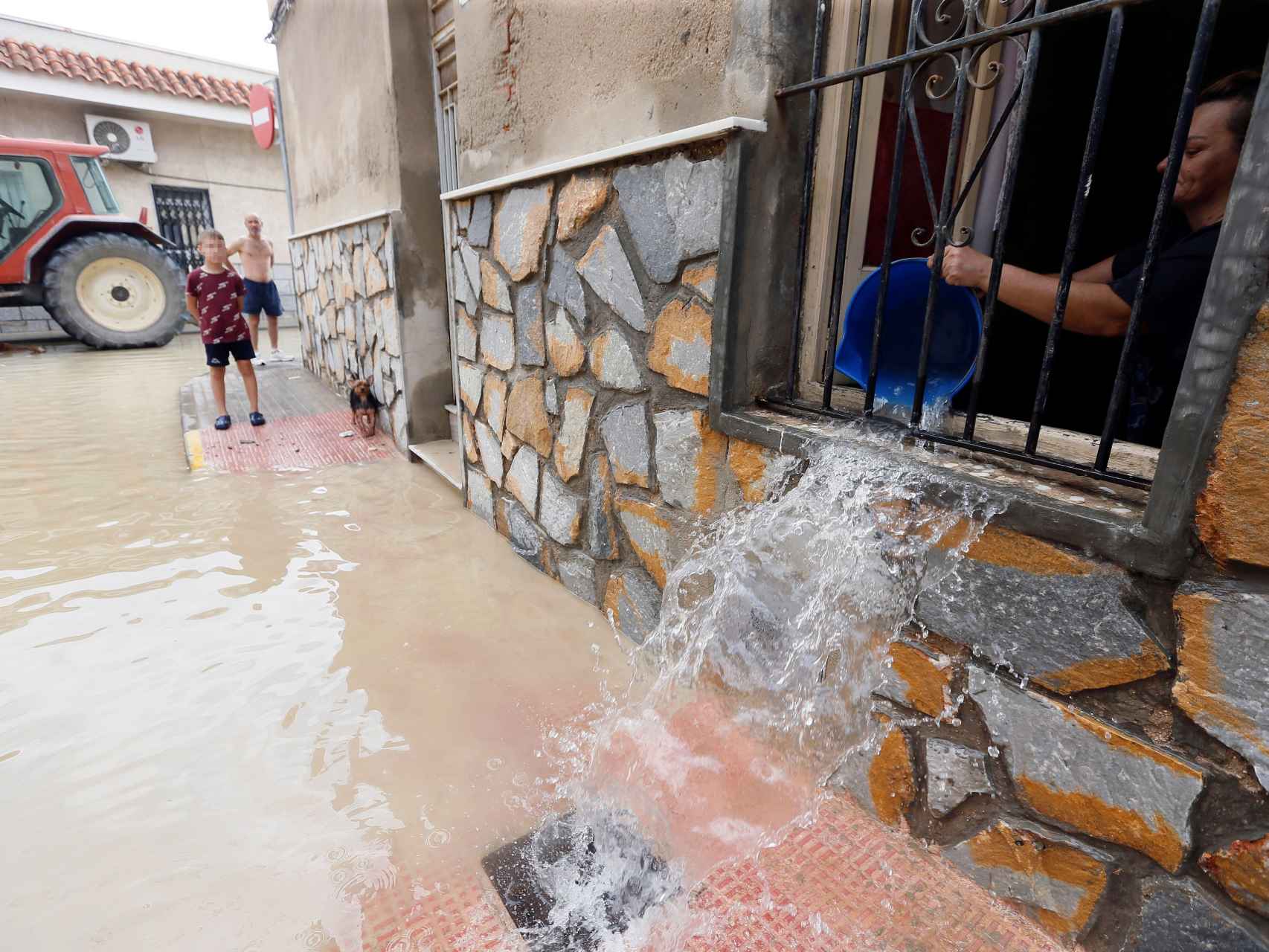 Una mujer achica el agua que ha inundado su casa en Dolores (Alicante)